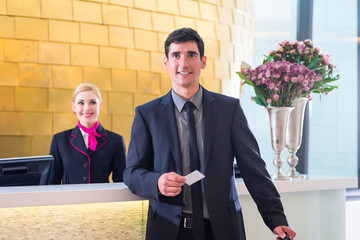 Hotel receptionist check in man giving key card