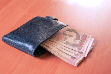 Hundred Ukrainian hryvnia banknotes in black purse