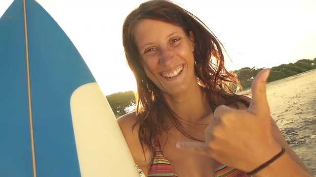 Smiling young woman showing surf sign with her hand