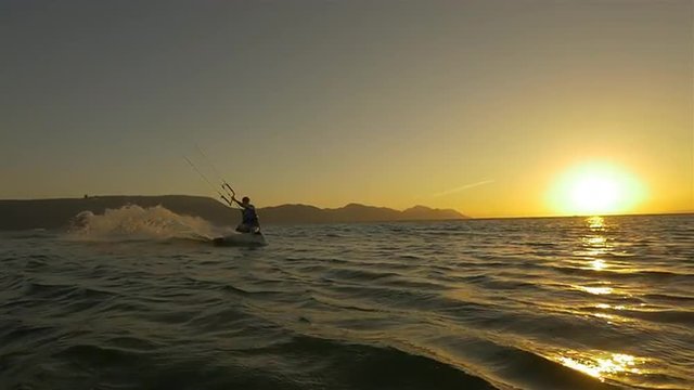 SLOW  MOTION: Kiteboarder jumping at golden sunset