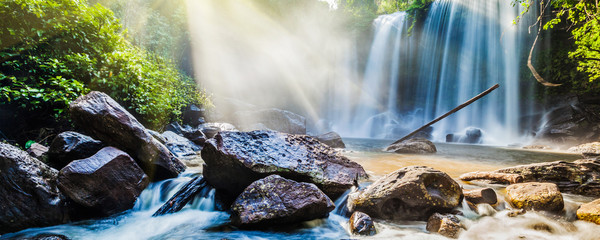 Tropical waterfall in jungle with sun rays