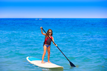Fototapeta na wymiar Kid paddle surf surfer girl with row in the beach