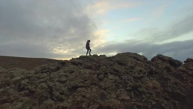 AERIAL: Woman hiking up on the edge of volcanic crater