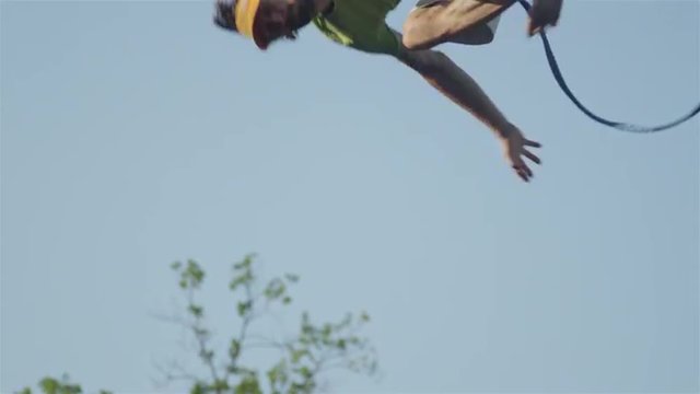 CLOSE UP of mans feet balancing and falling off slackline