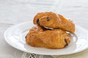 croissants with chocolate filling on a white plate, French pastries. side and top view, backlit, high-key.