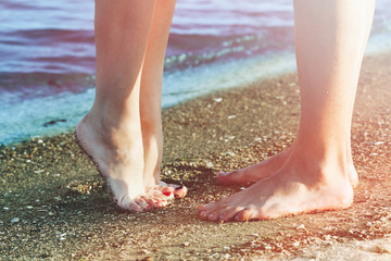 Male and female legs on sand of beach