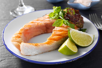 Tasty grilled salmon with greens on table close up