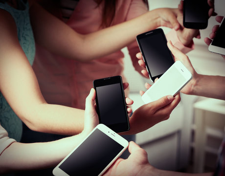 Many hands holding mobile phones close up