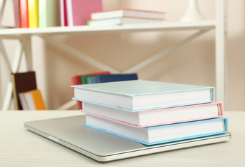 Stack of books with laptop on table close up