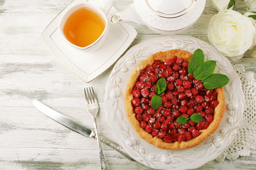 Tart with raspberries and tasty tea, on color  wooden background