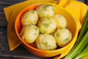 Boiled potatoes with greens in bowl on table close up