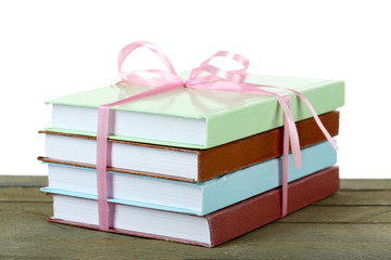 Stack of books with ribbon on light background