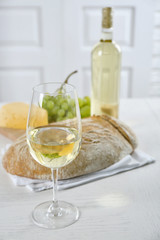 Still life of wine, grape, cheese and bread on light background
