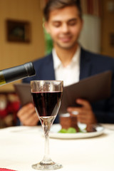 Young attractive man at the restaurant. Focus on wine glass