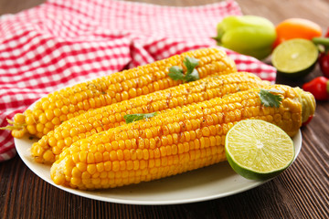Appetizing grilled corn served with vegetables and plaid pattern napkin