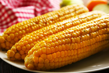 Appetizing grilled corn served with vegetables and plaid pattern napkin