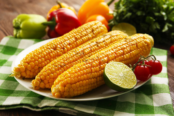 Appetizing grilled corn served with vegetables and green plaid pattern napkin