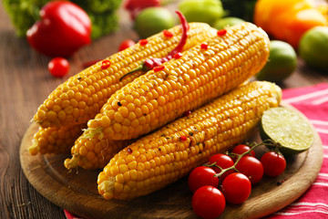 Obraz na płótnie Canvas Grilled corn served with vegetables on rustic round plate