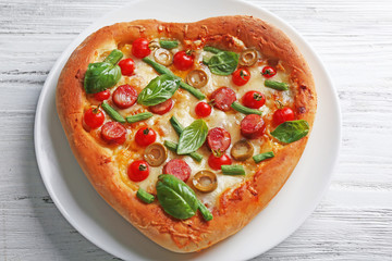 Delicious heart shaped pizza on wooden background