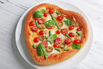 Delicious heart shaped pizza on wooden background