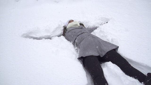 SLOW MOTION: Young woman making snow angels