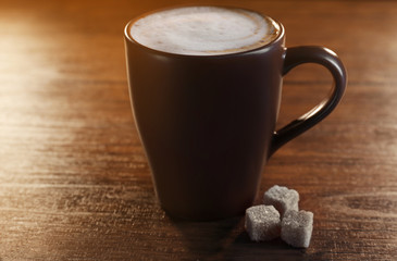 Tasty hot coffee with three pieces of sugar on wooden background