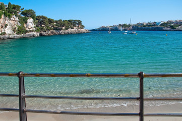 Beach in Porto Cristo with turquoise water and blue sky on a sunny summer day in Mallorca, Balearic islands, Spain.