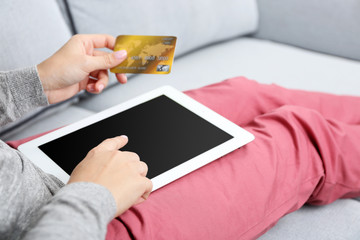 Concept for Internet shopping: woman with digital tablet and credit card sitting on sofa, at home