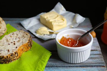 Tasty jam in the bowl, butter and fresh bread on green napkin close-up