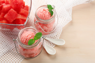Watermelon ice cream in glass jars  on color wooden background