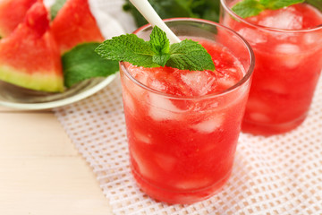 Cold watermelon drinks in glasses, on wooden table background