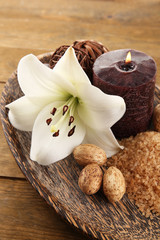 Spa composition with lily flower, candle and sea salt in bowl on wooden table