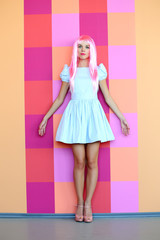 Portrait of beautiful woman with pink hairstyle on bright wall background