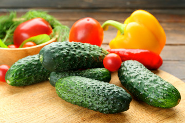Composition of cucumbers, tomatoes and sweet peppers circles on wooden background