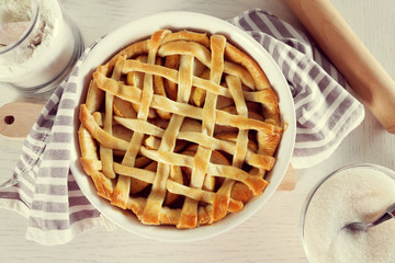 Homemade apple pie on wooden table, on light background