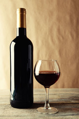 A bottle of red wine and a glass on wooden table