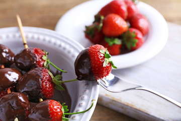 Served table with delicious strawberries in chocolate on wooden background