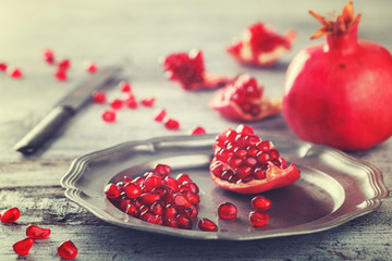 Juicy pomegranates,whole and broken vintage on a metal plate.Toned image. Vintage styleselective focus.