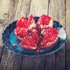 Ripe pomegranate fruit on the blue plate.Toned image. Vintage style.selective focus.