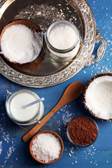 Homemade candies in coconut flakes and ingredients on color wooden background