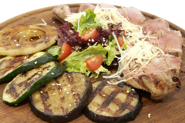 meat roasted on a grill with vegetables on a wooden plate