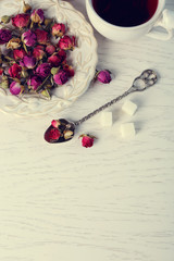 Tea and tea rose flowers on table closeup