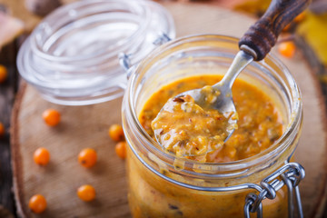 Twisted sea-buckthorn berries with sugar in a glass jar,jam useful.Autumn still life.selective focus.