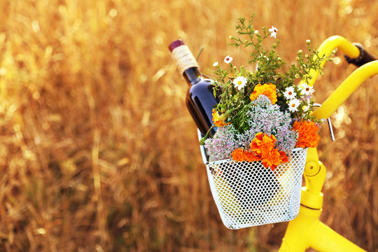 Fototapeta Bicycle with flowers and bottle of wine in metal basket closeup, outdoors