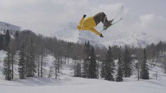 AERIAL SLOW MOTION: Freestyle skier jumping over big air kicker