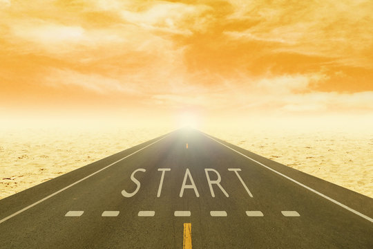 road through the desert with sign start on asphalt at sunset