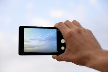 Man using smart phone for taking photo of beautiful sky