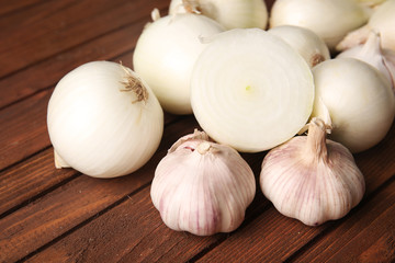 Fresh whole peeled onions with garlic on wooden background