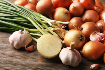 Fresh different onions with garlic on wooden background