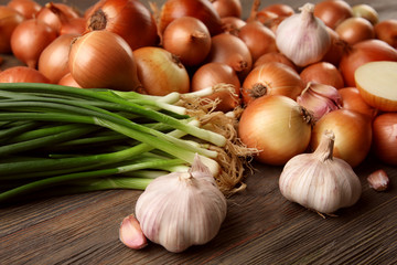 Fresh different onions with garlic on wooden background